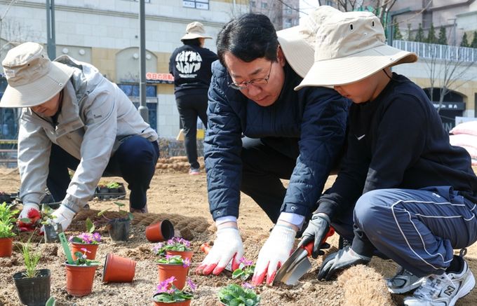 정명근 화성특례시장(가운데)이 21일 동탄여울공원에서 화성특별정원에 아이와 함께 꽃을 심고 있다