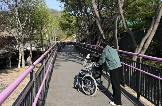 휠체어 이용객이 무장애 데크길을 이용해 진달래동산으로 이동하고 있다.